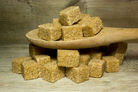 Cubes brown cane sugar and spoon on wooden backgroundの写真素材