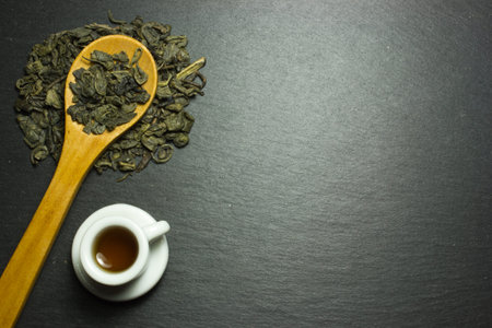 Cup and tea in a wooden spoon on a dark background. The view from the top.