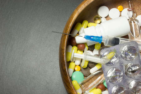 A wooden plate with a syringe and pillsの写真素材