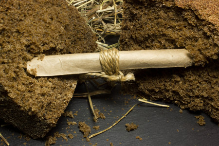 Black rye bread on the background of hay. Inside is a note, a message.