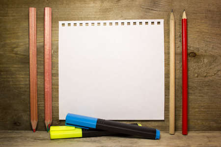 Pencils, markers and a white sheet of paper on wooden backgroundの写真素材