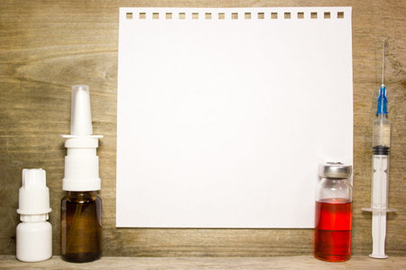 The syringe, ampoule and a white sheet of paper on wooden backgroundの写真素材