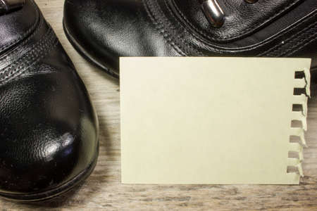 Black boots and empty paper on wooden backgroundの写真素材