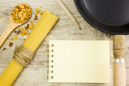 The pasta, paper and pan on wooden tableの写真素材