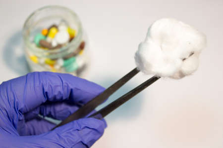 A piece of medical cotton in the tweezers on white backgroundの写真素材