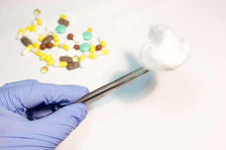 A piece of medical cotton in the tweezers on white backgroundの写真素材