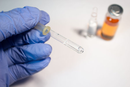 Medical pipette in one hand and a vial of white background