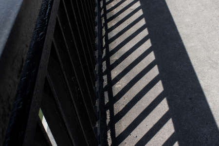 The shadow of the bridge railing on the pavementの写真素材