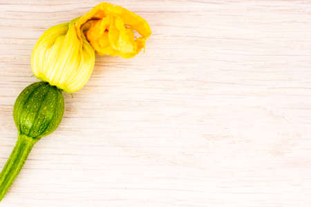 Green zucchini and blossoms on wooden tableの写真素材