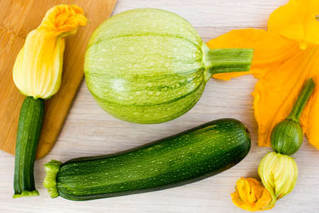 Green zucchini and blossoms on wooden tableの写真素材
