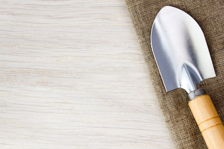 Trowel and tools on sackcloth on wooden table