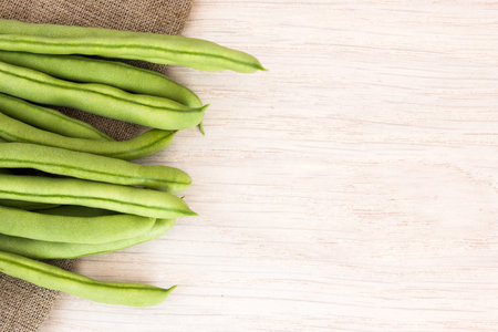 Green beans on sackcloth on wooden table