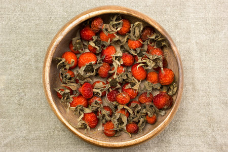 Dried berries rose hips in a bowl on burlap on the table