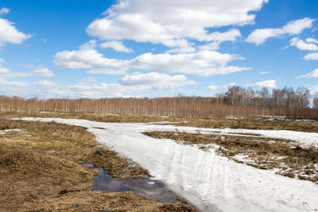 The road under the snow in spring fieldの写真素材