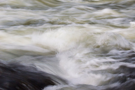 A powerful stream of mountain river. The fast current of water.