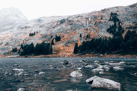 Mountain lake with reflection in the mirrored surface of the rocks in cloudy rainy weather. The beauty of the mountain country and nature.の写真素材