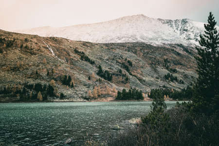 Mountain lake with reflection in the mirrored surface of the rocks in cloudy rainy weather. The beauty of the mountain country and nature.の写真素材