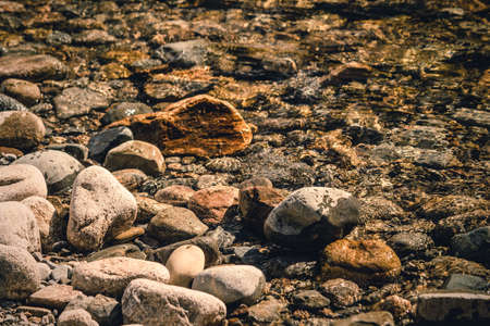 Stones, pebbles and sand on the shore of a mountain riverの写真素材