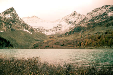 Mountain lake with reflection in the mirrored surface of the rocks in cloudy rainy weather. The beauty of the mountain country and nature.の写真素材