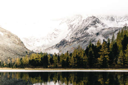 Mountain lake with reflection in the mirrored surface of the rocks in cloudy rainy weather. The beauty of the mountain country and nature.の写真素材