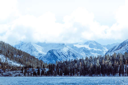 Mountain lake with rocks on the shore, winter fog over the water surface. Travel to the mountains on foot, wildlife.の写真素材