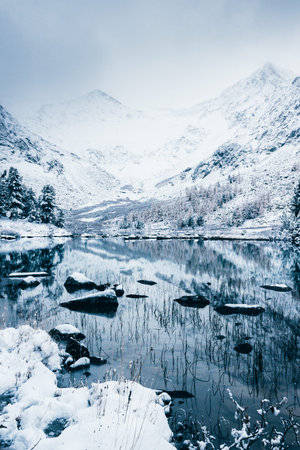 Mountain winter lake with the reflection of rocks in the water surface. High-altitude beautiful lake...