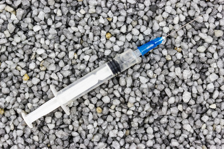 Plastic syringe on the fine gravel. Medicine, medicine. Taking drugs.