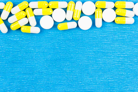White and yellow pills on a blue background. Medical medicines for health.の写真素材