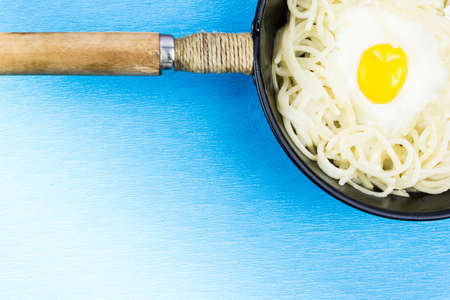 Pan with spaghetti and egg on a blue background.の写真素材