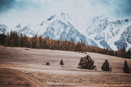 Beautiful view of the hills with a dirt road to the snowy peaks. Colorful mountain valley with rocks.の写真素材