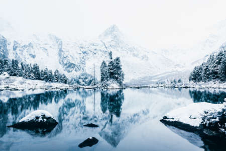 Mirror surface of the winter lake with a mountain range. First snow in the mountains. Travel to the national Park in the Altai mountains.の写真素材