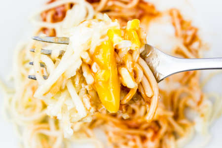 Scrambled eggs and spaghetti with ketchup on the fork.の写真素材