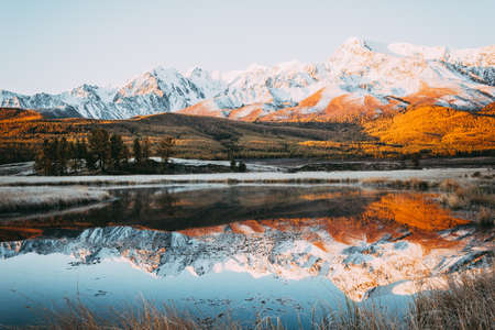 The peaks of the cliffs on the horizon at the colorful sky. Mirror surface of the lake in the mountain valley.  Autumn weatherの写真素材