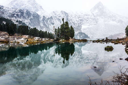 Reflection of mountains with snowy peaks in the mirror of the lakeの写真素材