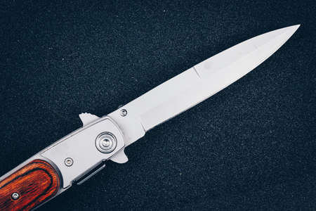 Folding knife on black asphalt. Instrument of crimeの写真素材