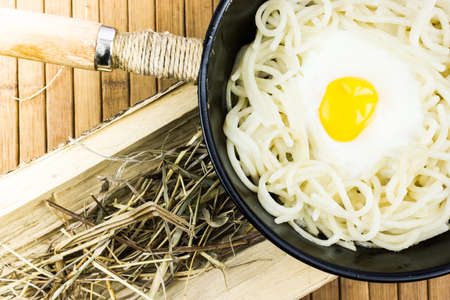 Fried egg and spaghetti in a black pan on a wooden table. Cooking at home, rustic food.の写真素材