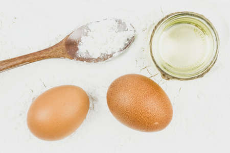Egg, wooden spoon and a glass of sunflower oil for baking, kneading dough. Homemade meal made of flour.の写真素材