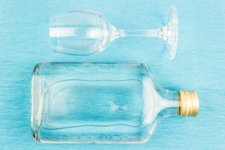 Glass and flat glass bottle on a blue background. Alcoholic beverages, vodka.