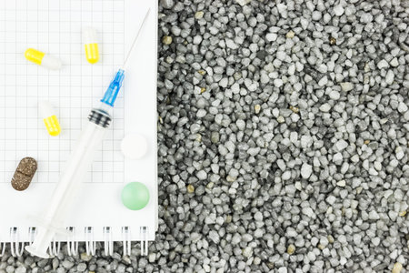 Plastic syringe and tablets on gray gravel