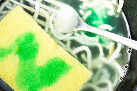 Sponge for washing dishes with green cleaning gel. The process of washing dishes, frying pans.