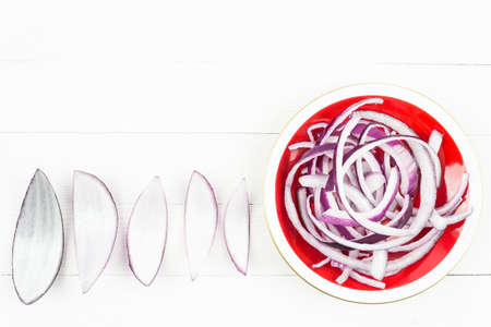 Slices of red fresh onion on a white table. Copy space for textの写真素材