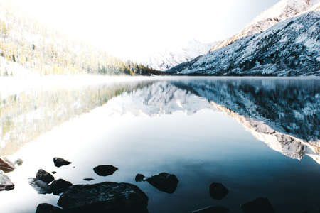 Mirror surface of the mountain lake. Beautiful nature, a trip to the mountains in a national Park in Altai Republic. Cloudy weather in winter.の写真素材