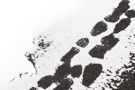 Footprints in fresh snow on the sidewalk. Snow and ice in the city.