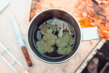 Tea for the traveler. Metal mug and knife on the wooden table.
