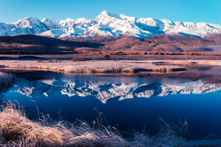 Reflection of snowy mountain ridge in lake. Autumn in mountains. Travel Altai.