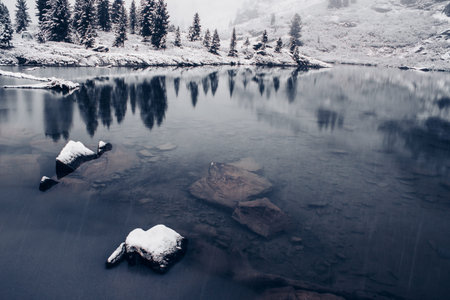 Winter lake, snow in coniferous forest on shore of mountain lake