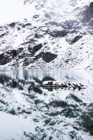 Reflection of snow rocks in mountain lake. Winter in river valleyの写真素材