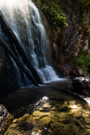 Scenic waterfall on mountain river in summer forest. Travel along river.