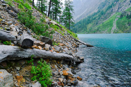 Rocky shore of blue lake. The surf of turquoise sea, waves come to shoreの写真素材