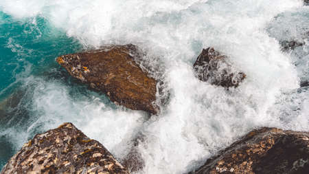 Turquoise water in river with stone shore. Sea tide, seething blue water in mountain streamの写真素材